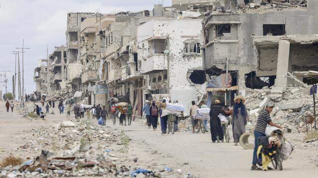 Families return to Khan Yunis, southern Gaza, on Oct. 12, 2025, surveying the widespread destruction in the city and salvaging belongings.